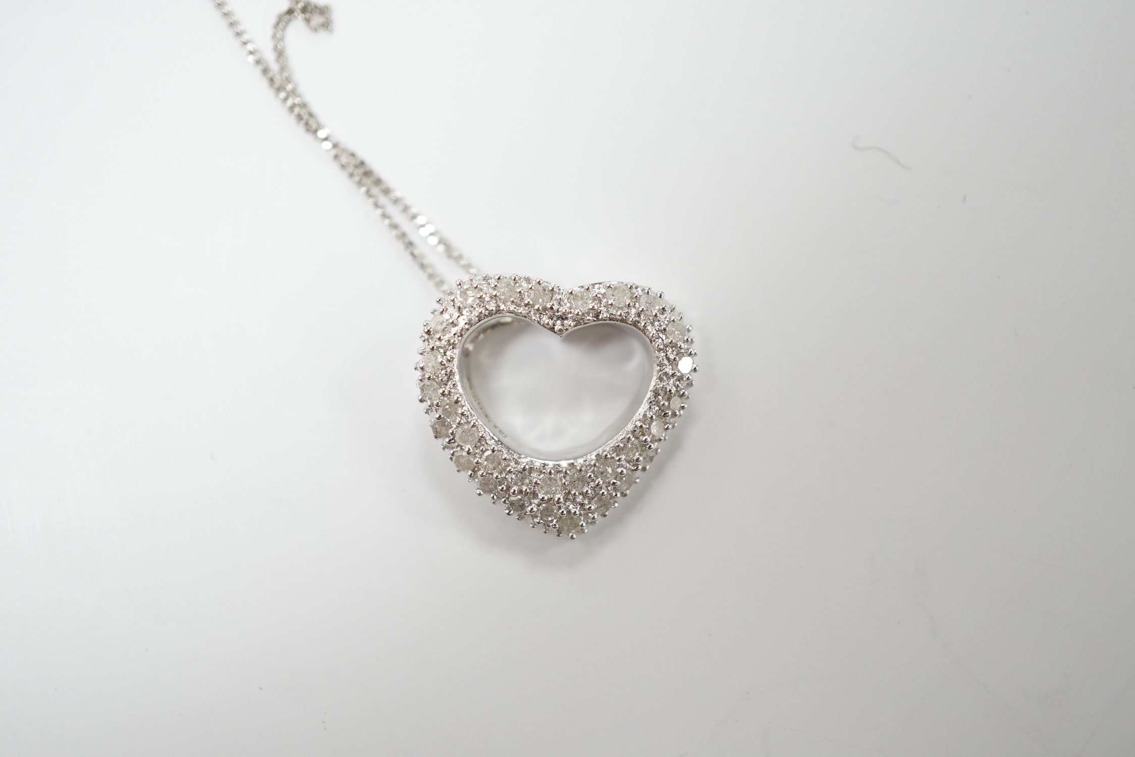 A modern 375 white metal and diamond chip set heart shaped pendant on chain, overall 42cm, gross weight 2.4 grams.